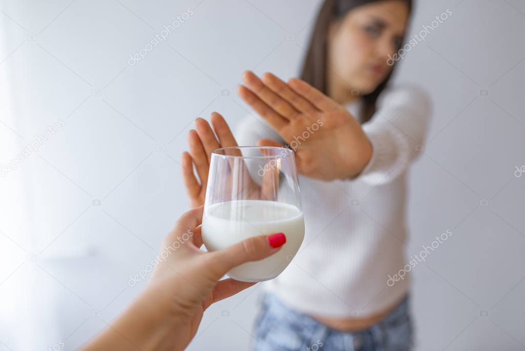 Close-up Of A Woman Rejecting Glass Of Milk At Home. Woman with milk allergy isolated. Lactose intolerance. Dairy Intolerant Woman refuses to drink milk