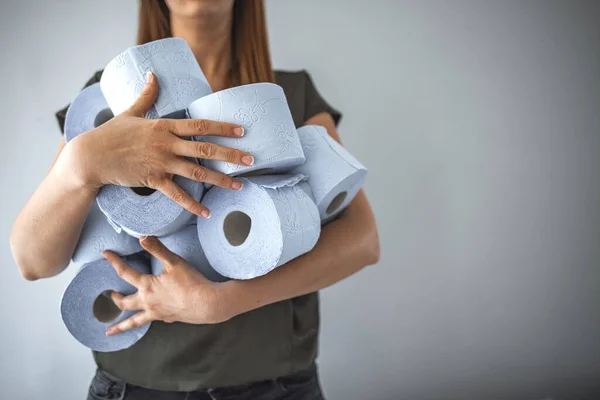 Woman storing tissue toilet paper during Coronavirus outbreak or Covid-19. People are stocking up toilet paper for home quarantine from crownavirus. Woman holds many rolls of toilet paper