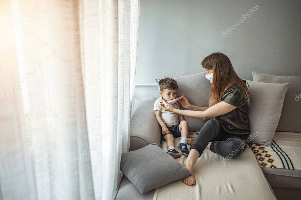 Little boy and mom in medical mask. Mother puts on her baby sterile medical mask. Child, wearing face mask, protect from infection of virus, pandemic, outbreak and epidemic of disease on quarantine.