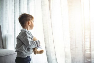 Karbondioksit 19 için bir hafta karantina yaptıktan sonra pencereden bakan sevimli bir çocuk. Koronavirüs salgınını önlemek için karantinada kalın. Önleme salgını.