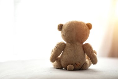 Koronavirüs salgını sırasında karantina ve kendini izole etme. Sosyal uzaklık. Evde kal. Tıbbi maske takan yumuşak oyuncak ayıcık evde oturup pencereye bakıyor. Karantina, virüs koruması. Boşluğu kopyala. 