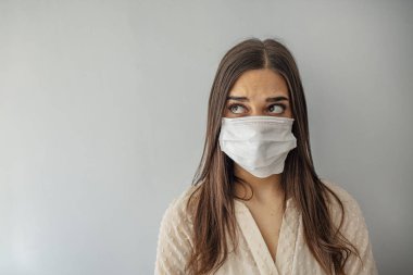 Kadın koruyucu yüz maskesi takıyor. Yüz maskeli genç bir kadın. Gözünde korku olan maske takan bir kadının yüzü. Evinde kirlenme maskesi takan güzel bir genç kadın.