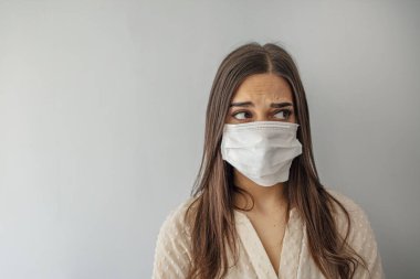 Kadın koruyucu yüz maskesi takıyor. Yüz maskeli genç bir kadın. Gözünde korku olan maske takan bir kadının yüzü. Evinde kirlenme maskesi takan güzel bir genç kadın.