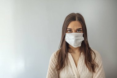 Gri arka planda tıbbi maskeli bir kadın. Sağlıklı yaşam tarzı, hastalıklı hastalık tedavi konsepti. Kopyalama alanı oluşturun. Salgın, tehlikeli ve ölümcül virüs, enfeksiyon konsepti