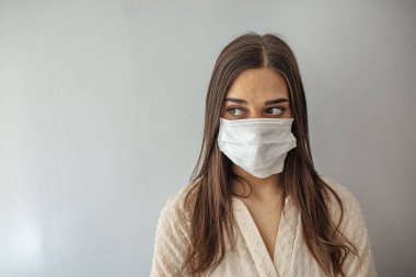 Gri arka planda tıbbi maskeli bir kadın. Sağlıklı yaşam tarzı, hastalıklı hastalık tedavi konsepti. Kopyalama alanı oluşturun. Salgın, tehlikeli ve ölümcül virüs, enfeksiyon konsepti
