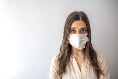 Solunum maskeli kız. Maskeli çekici kadın kameraya bakıyor. Soğuk algınlığı, grip, virüs, bademcik iltihabı, akut solunum hastalığı, karantina, salgın. Korunma maskeli genç kadın.