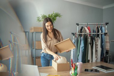 Kadınlar, küçük işletmelerin sahibi kutular içinde ürünleri paketliyor, teslimat için hazırlıyorlar. İnternette sattığı ürünleriyle birlikte paket paketleyen kadınlar. Küçük işletme sahibi