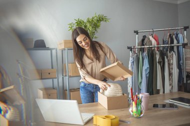 Evde çalışan bir kadın, internetten mal satıyor. Çevrimiçi alışveriş birçok insanı mutlu eder. İnternette sattığı eşyaları paketleyen kadın. Gönderdiğim eşyalar mükemmel olmalı. 
