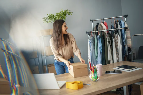 Women, owener of small business packing product in boxes, preparing it for delivery. Women packing package with her products that she selling online. Small business owener