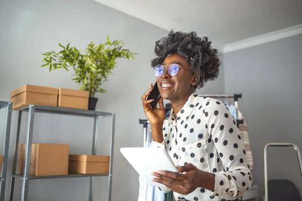 オフィスでデジタルタブレットを使用して美しいアフロアメリカの若い女性は 良いニュースを受信し 顔を閉じてください 彼女の机に座っている間に電話で話して魅力的な若い女性のショット — ストック写真