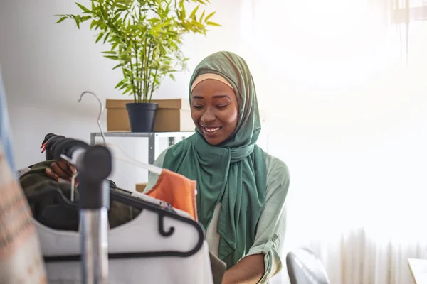 誰もがオンラインショッピングを行う 彼女がオンラインで販売する女性の梱包アイテム 起業家としてのムスリム女性デザイナー 女性ムスリムデザイナーチェックハング服でテーラーショップ — ストック写真