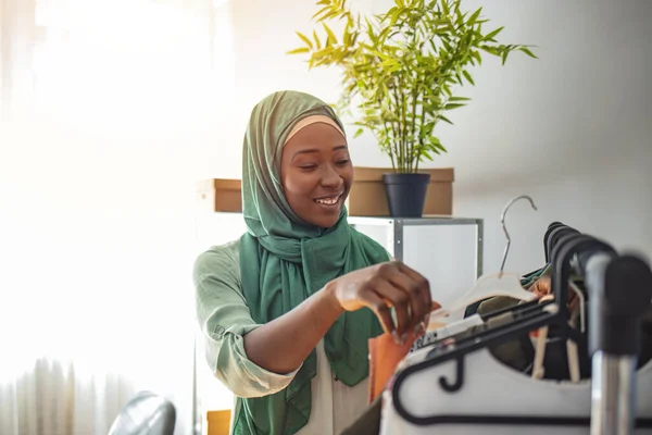 テーラーショップで働くスタートアップビジネスオーナーとしてのムスリム女性デザイナー 小規模事業主 ワークショップで働く美しい若いアフリカ人女性 オンラインショッピングは多くの人々を幸せにします — ストック写真