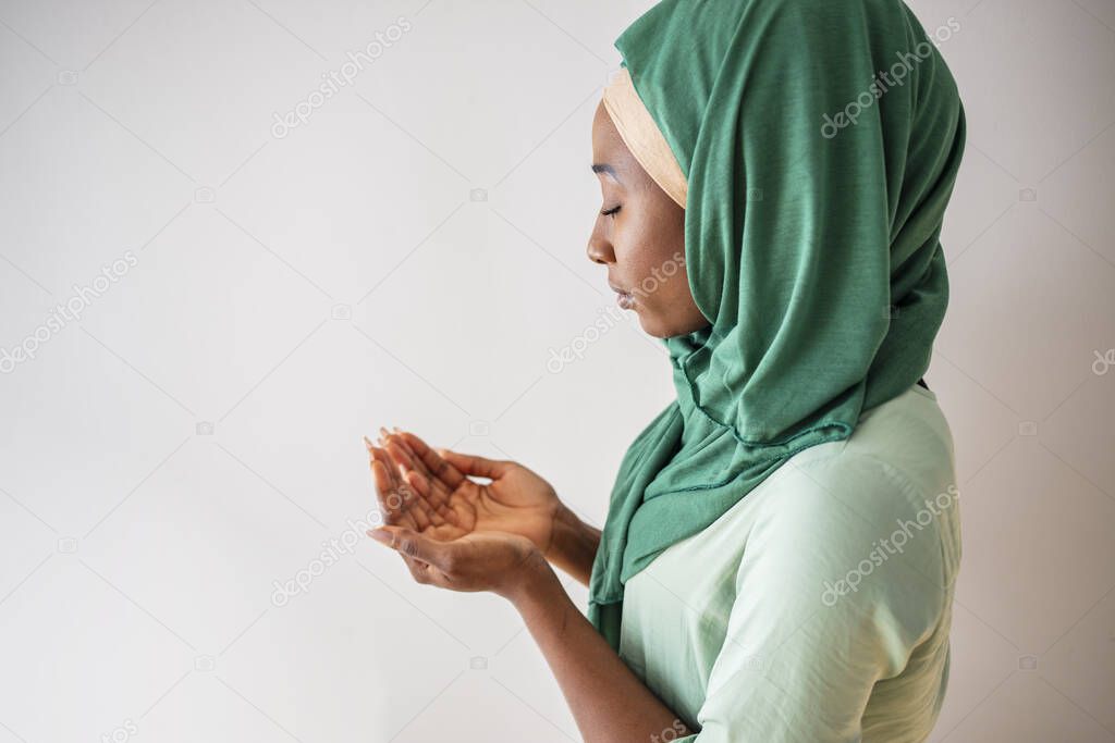 Close up picture of a young muslim woman praying. Young Muslim woman Praying with folded hands. She has a green veil covering her head. Young muslim woman praying in mosque