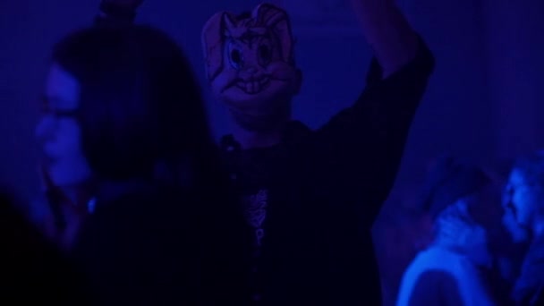 Muž v masce tančí v klubu, dav lidí tančí na večírku — Stock video