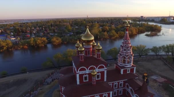 Luftdrohne schoss die Kirche an einem sonnigen Sonnenuntergang vor dem Hintergrund des großen Flusses, der über die Ufer trat — Stockvideo