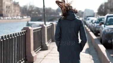 Mutlu kız boyunca Waterfront beyaz kulaklık, müzik dinlemek, şehrin her yerinde çalışan bir şık Denim ceket giyinmiş