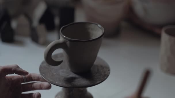 Joven alfarero trabaja en taller, pinta taza, primer plano tiro manos de alfarero — Vídeos de Stock