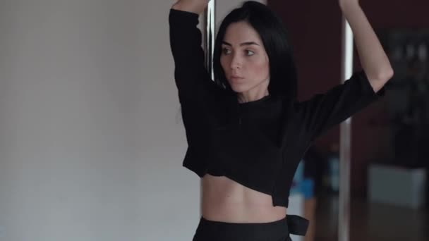 Menina sexy dançando no pólo, com cabelo preto longo e roupas pretas — Vídeo de Stock