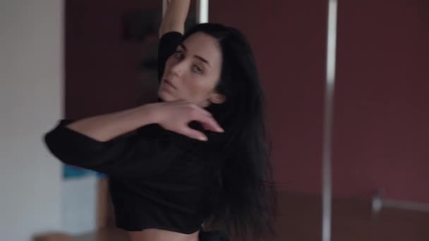 Szexi fiatal lány táncol a pole, hosszú, fekete haja és a fekete ruhák — Stock videók