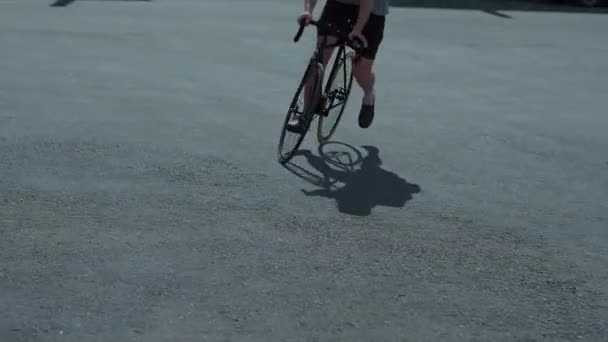 ひげを生やした男は夏の日、黒のショート パンツ、グリーン キャップ ガラス、バックパック、ゴミ箱の背景にブラック ヴィンテージ自転車に乗っています。 — ストック動画