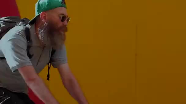 Egy nagy szakállú, a háttérben a sárga fal lovaglás kerékpárosok — Stock videók