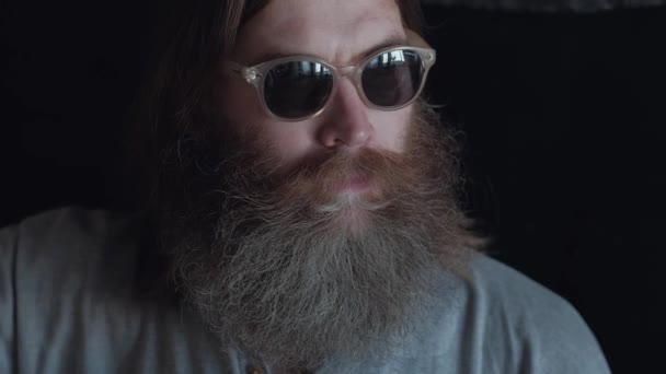 Portrait d'un homme barbu en lunettes sur fond noir — Video