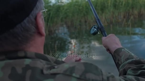 Rybář v maskování a černou čepici špíz návnadu na háček — Stock video