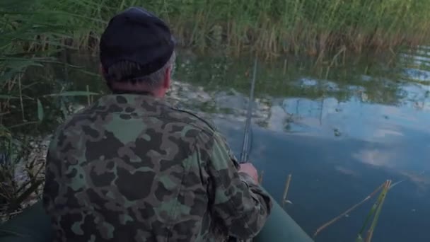 Le pêcheur est assis dans le bateau et attend que le poisson mord — Video