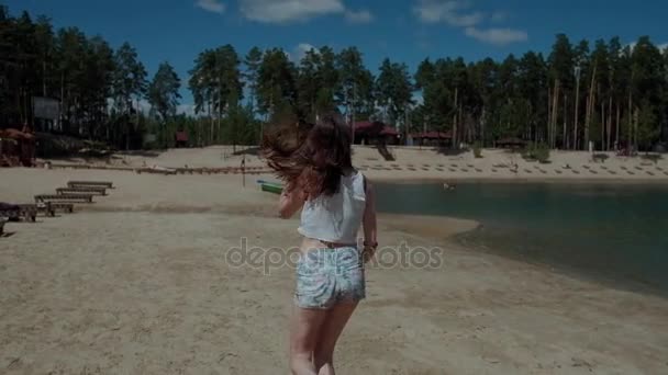 Mujer atractiva emocional, con el pelo largo que fluye corre en la playa sonriendo y riéndose de la cámara - cámara lenta — Vídeo de stock