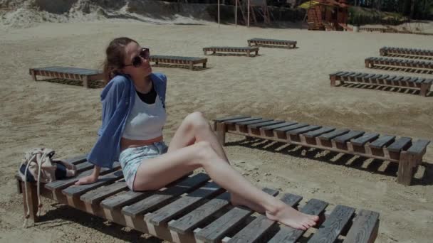 Girl on Vacation Resting on the Beach Lying on a Sun Lounger, Blowing a Light Breeze, Enjoying and Rejoicing in the Sun — Stok Video