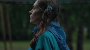 Slowmotion - kız baş, Pigtails yağmurla sonra yürüyüş göletlerde, yağmurlu havalarda parlak renkli yağmurluk, içinde giriyorum mavi lastik çizmeler