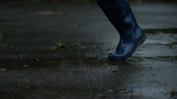Primer plano: chica con botas de goma azul y leyenda negra pateando una lata de cerveza, en clima lluvioso, para el alcoholismo — Vídeos de Stock