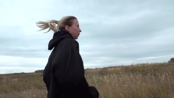 Жіноча блондинка заходить в чорний анорак — стокове відео