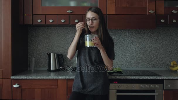 Meisje met bril eet ontbijt in de keuken. — Stockvideo