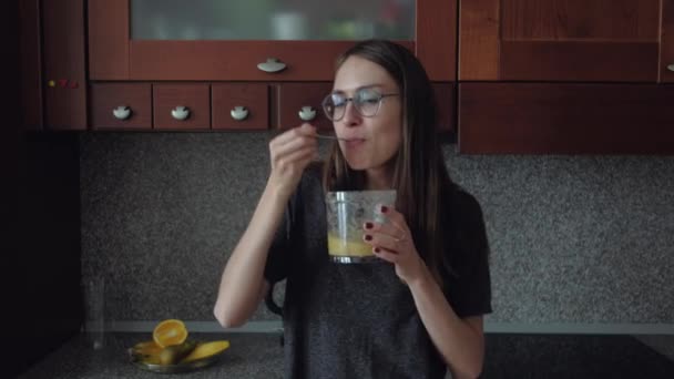 Γυναίκα με γυαλιά τρώει πρωινό στην κουζίνα. — Αρχείο Βίντεο
