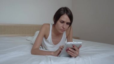 Yatak odasında bir tablet ile iyi görünümlü esmer