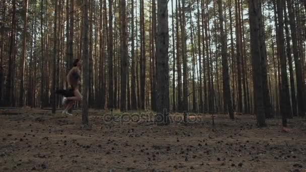 Flicka kör i skogen med stora tallar — Stockvideo