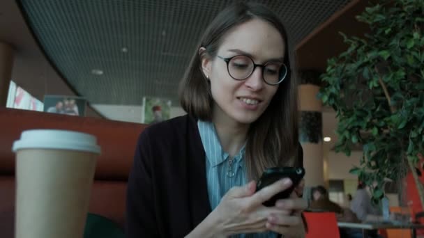 Roztomilý kavkazských dívka Bruneta hospodářství mobilní telefon v ruce s naštvaná, podrážděná vzhled. — Stock video