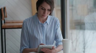 Sevimli kadın kafeteryada oturan ve dijital tablet kullanma
