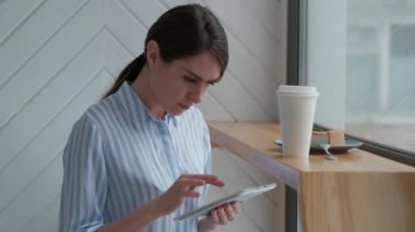 Sevimli kadın kafeteryada oturan ve dijital tablet kullanma