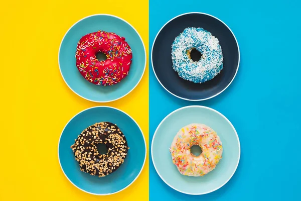 Taze iştah açıcı tabakta duran dört donut. Renkli sarı ve mavi arka plan..