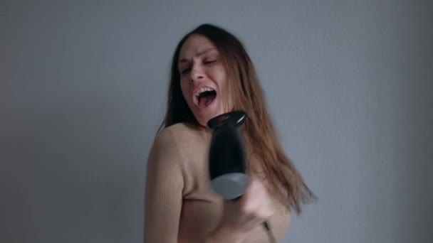 아름다운 젊은 여자가 헤어드라이어를 사용하며 노래하는 모습. — 비디오