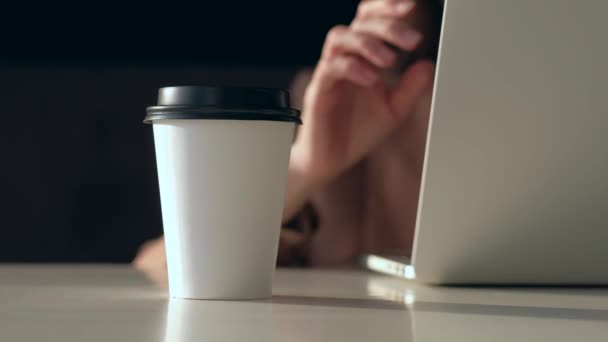 Concéntrate en la taza de café. Beber café femenino y trabajar en el ordenador portátil en el día soleado . — Vídeos de Stock