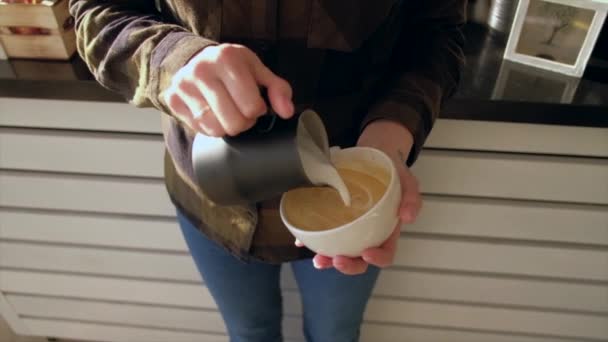 Close-up Barista handen gieten warme melk in koffie kopje voor het maken van Latte kunst. — Stockvideo