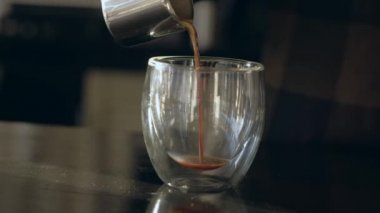 Barista taze yapılmış kahve şeffaf bir kupa dökülen..