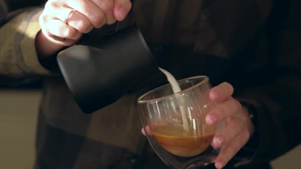 Zavřete Barista ruce, které nalévá teplé mléko v kávovém šálku za účelem vytvoření Latte grafiky. — Stock video