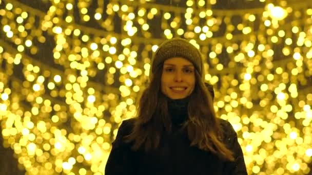 Porträt eines glücklichen Mädchens auf einer mit Weihnachtsbeleuchtung dekorierten Abendstraße. — Stockvideo