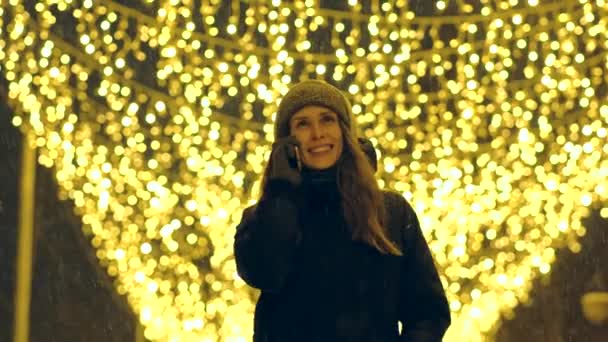 Porträtt av en lycklig flicka på en kvällsgata dekorerad med julbelysning. — Stockvideo