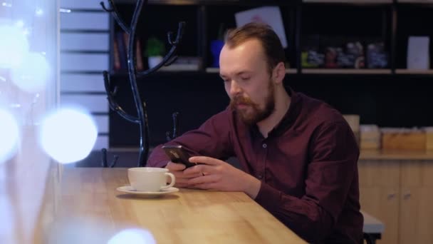 Чоловік використовує смартфон, п'є каву . — стокове відео