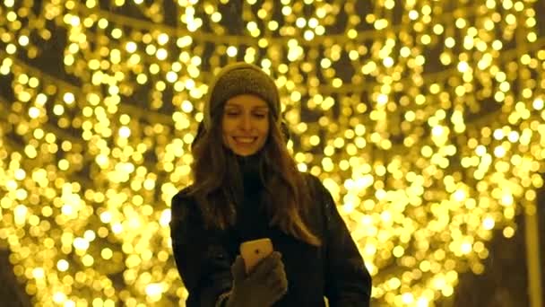 Portret van een gelukkig meisje op een avond straat versierd met kerstverlichting. — Stockvideo